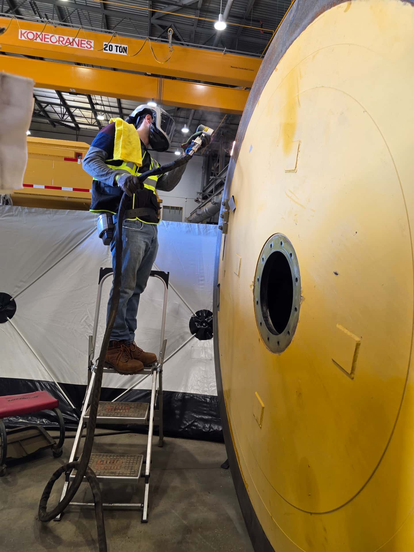 Northern Laser Cleaning facility with worker preparing large industrial vessel for laser treatment