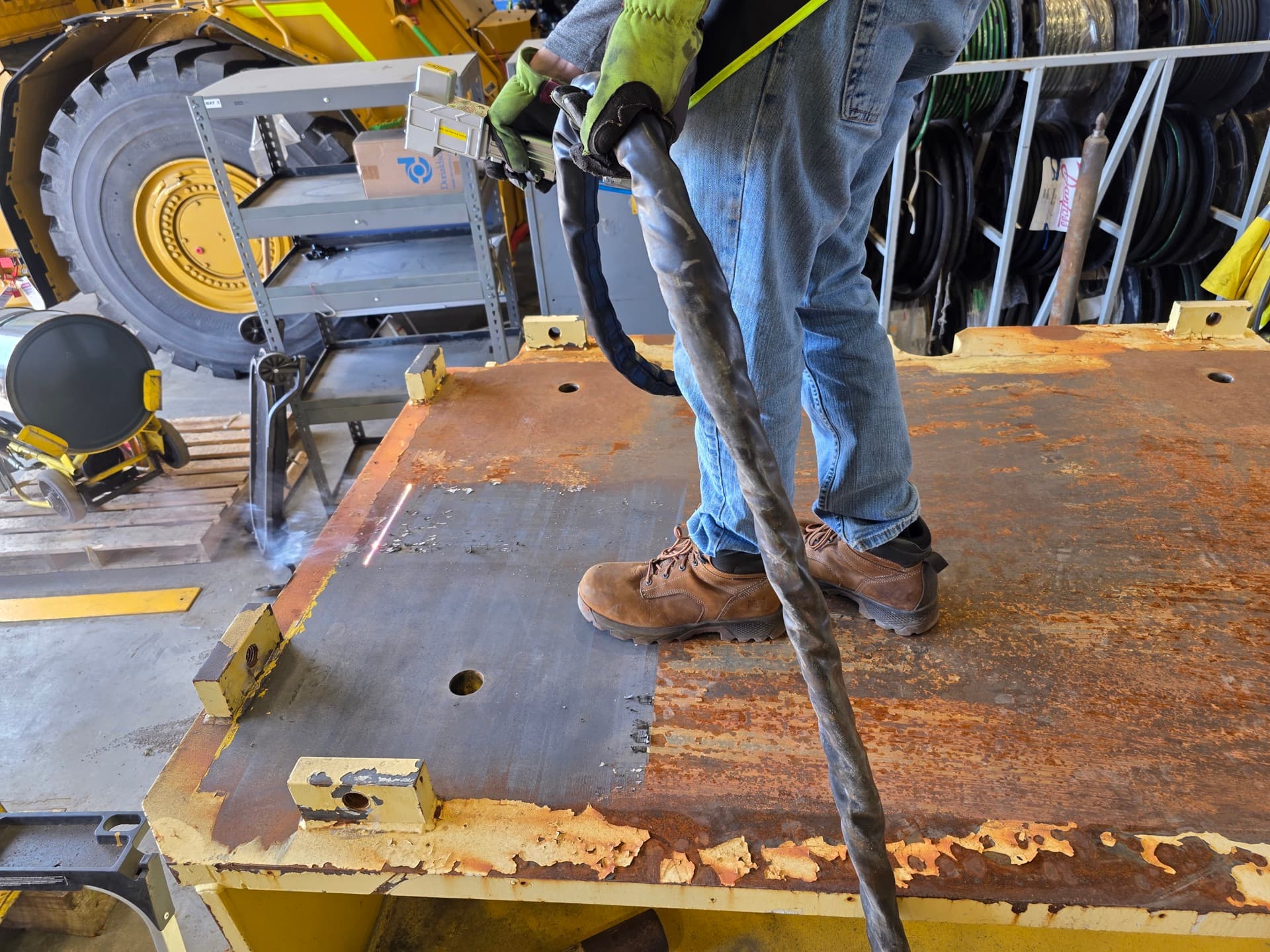 Laser ablation removing rust and corrosion from industrial metal plate, showing clear before and after contrast